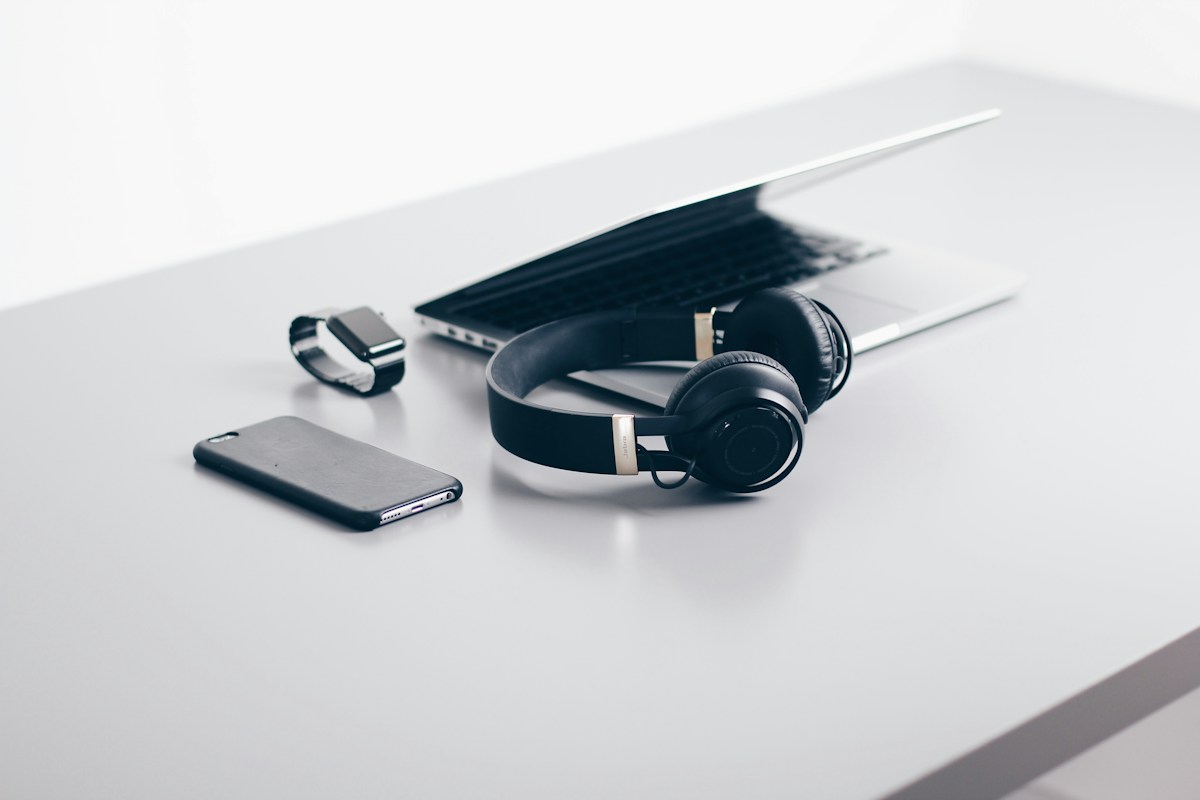 Laptop, phone, and headphones arranged on a desk