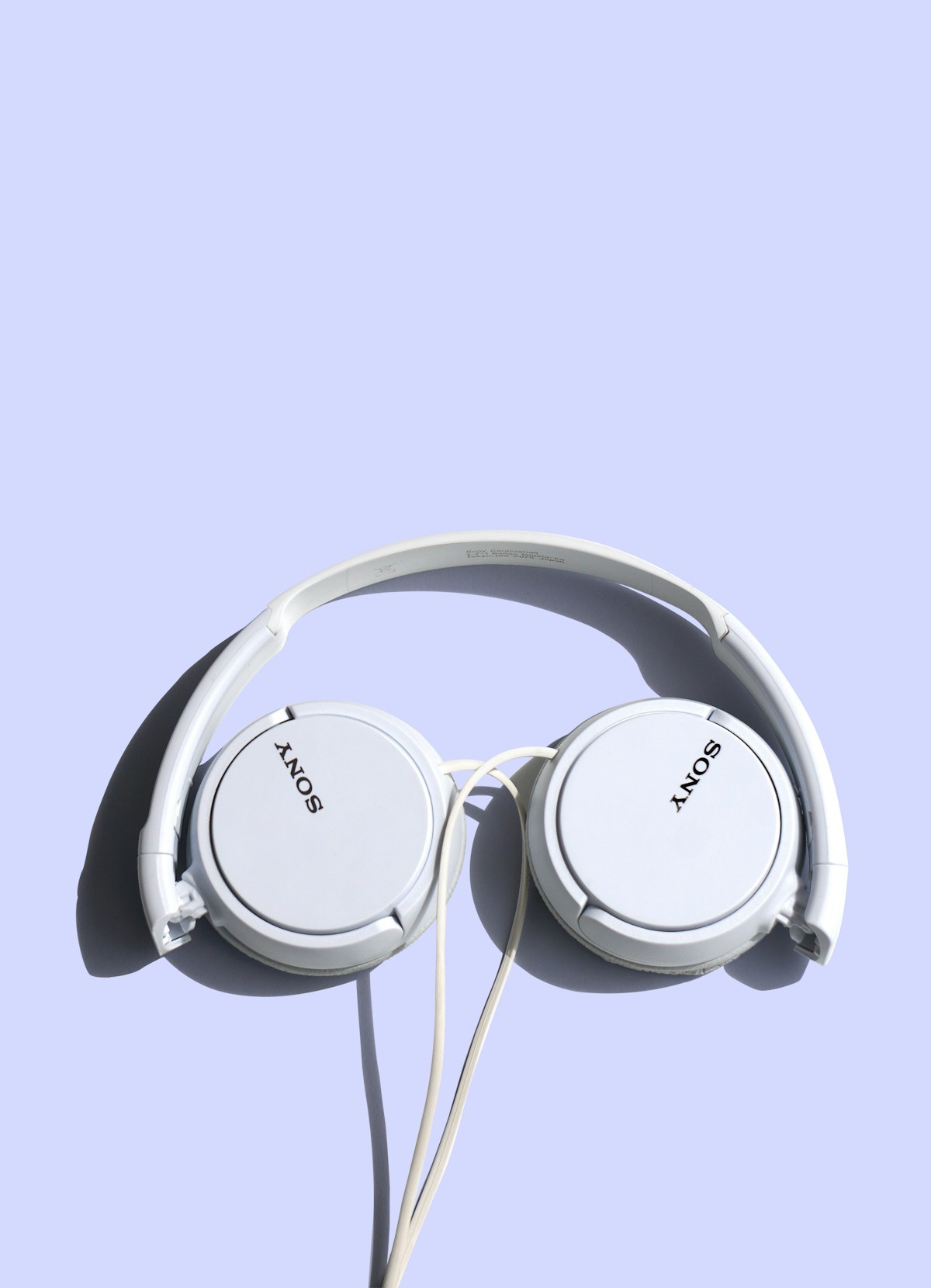 White over-ear headphones on a lavender surface