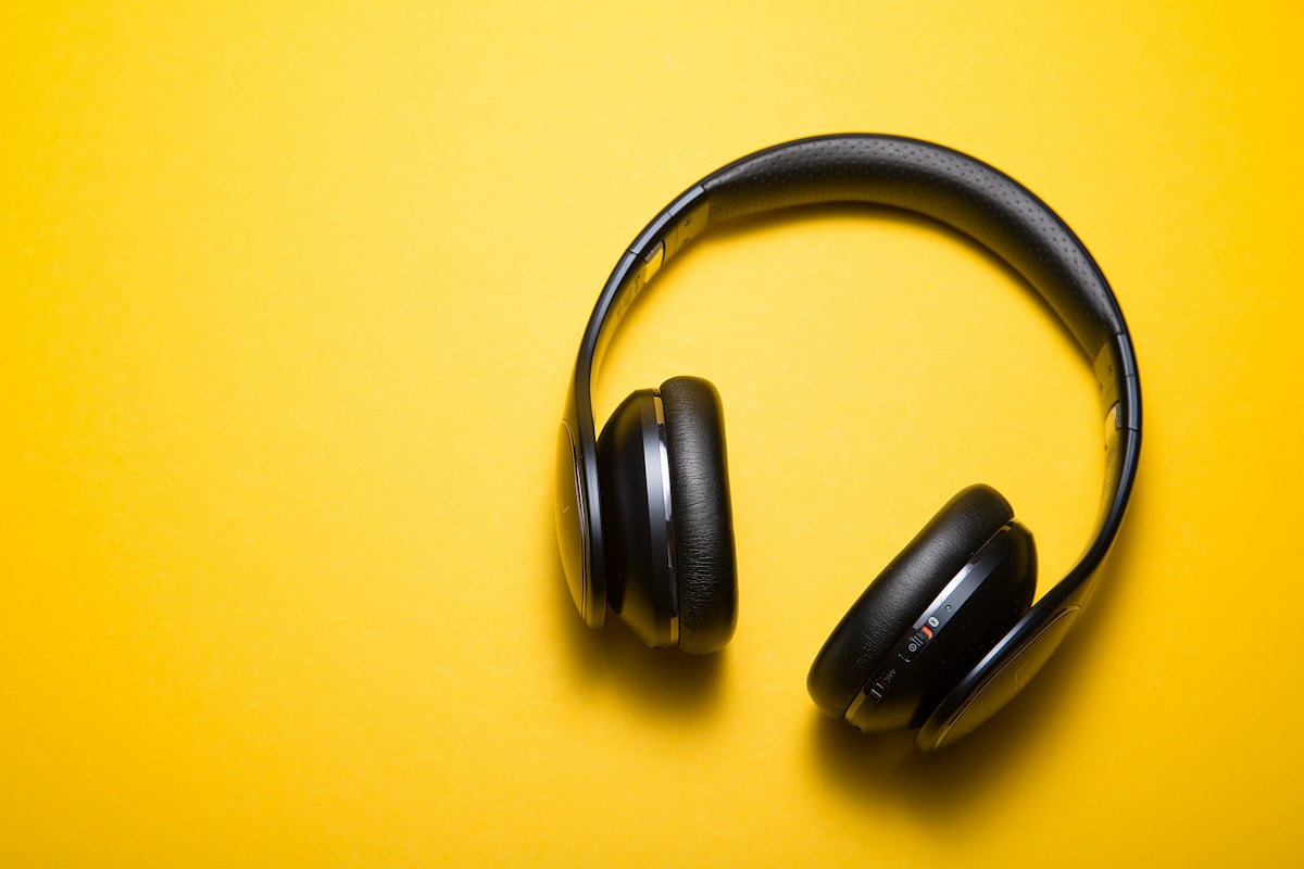 Black headphones against a warm yellow surface